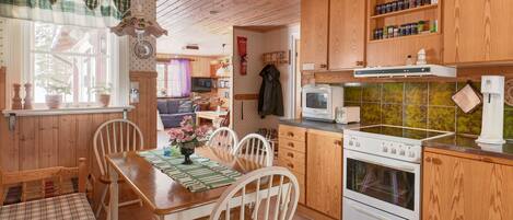 A cozy kitchen with wooden cabinets, a dining table with chairs, and a built-in oven.