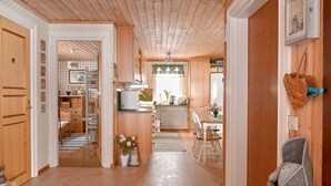 A spacious kitchen with wooden cabinets, a dining area with a table and chairs, and a cozy seating area with a chair and a rug. - Lillarmsjö-cottage, cottage with lake view. (Lillarmsjö)