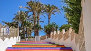 A staircase with rainbow-colored steps leading up to a white building with a fence.