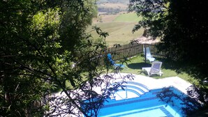 Un espace piscine offrant une vue sur une courClose et sur des collines lointaines.