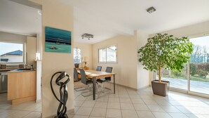 A spacious dining area with a wooden table and chairs, a potted tree, and a painting on the wall. - Heated, well-equipped house/pool between Lacs d'Annecy and Aix-les-Bains (Rumilly)