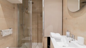 Ein modernes Badezimmer mit einer Duschkabine, einem Waschbecken und einem Spiegel.