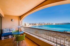 A balcony with a view of a beach and cityscape. - TOP LOCATION, exclusive, modern apartment right on the beach of S'illot TOP!  (S'Illot-Cala Morlanda)