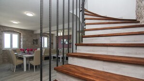 A modern staircase with wooden steps and metal railings, leading to a dining area with a white table and chairs. - NEW! Stone house in quiet location, heated pool + sea views, ideal for familys (Zivogosce)