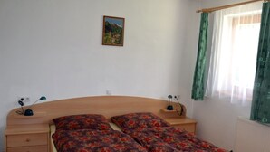 Ein Schlafzimmer mit einem hölzernen Bett, zwei Nachttischen, einer Wandlampe und einem Fenster mit Vorhängen.
