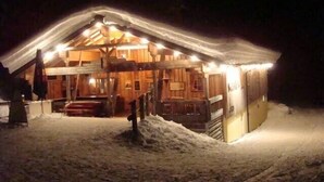 Une cabane en bois recouverte de neige, avec un toit en pente et une véranda.