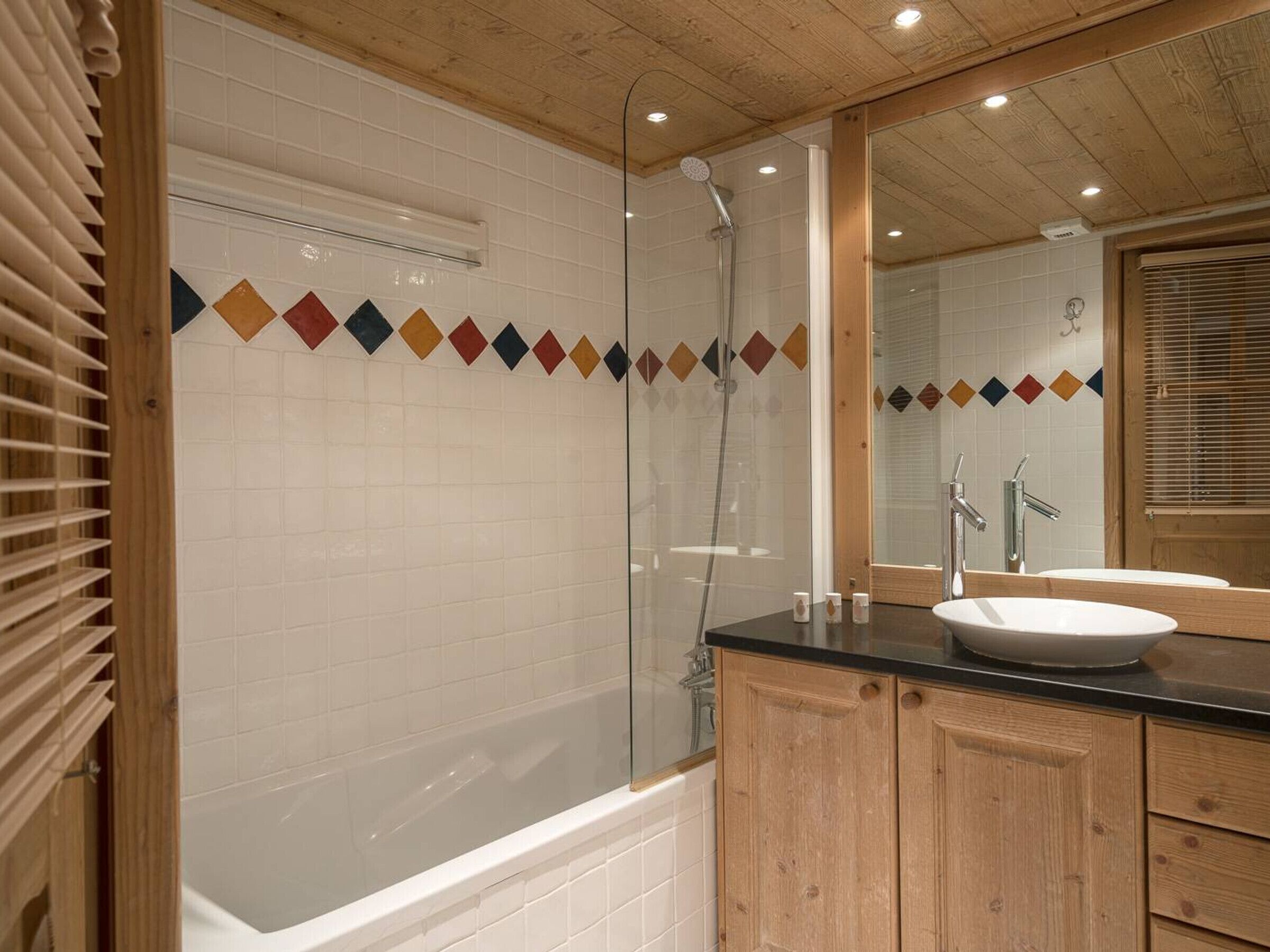 A modern bathroom with a glass-enclosed shower, a white bathtub, and wooden cabinetry.