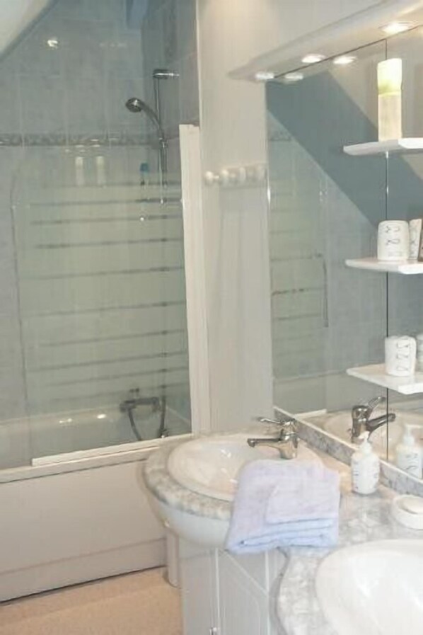 Un baño moderno con cabina de ducha de vidrio, lavamanos de mármol y un espejo grande.