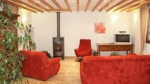 Un salón acogedor con chimenea, muebles rojos y televisor.