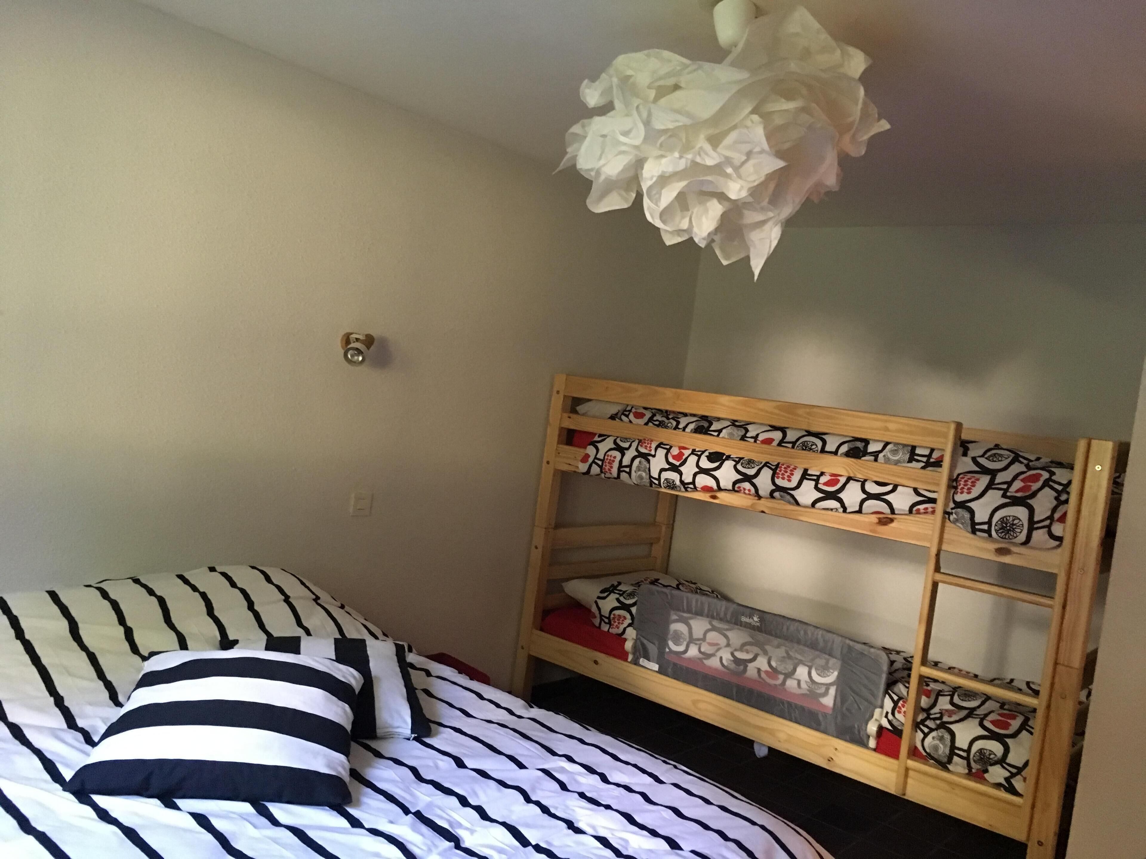 A bunk bed with patterned bedding and a ceiling light fixture.
