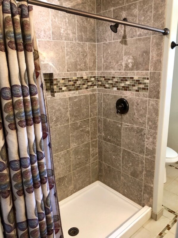 A shower area with a tiled wall, a showerhead, and a curtain.