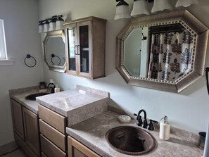 A bathroom with a sink, mirror, cabinet, and towel rack.
