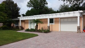 A modern two-story house with a garage, a well-maintained lawn, and a stone pillar. - Luxury, New Home - Serene and Private Vacation Oasis - Minutes from Siesta Key! (Sarasota)