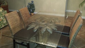 A glass-top dining table with woven chairs, surrounded by potted plants. - Luxury, New Home - Serene and Private Vacation Oasis - Minutes from Siesta Key! (Sarasota)