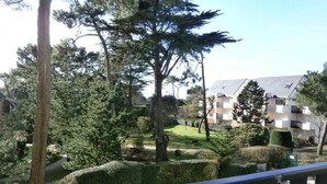Un quartier résidentiel doté d’une pelouse bien entretenue, d’arbres adultes et d’un immeuble avec des balcons.