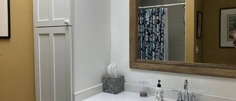 Un baño con tocador blanco, un espejo grande y un lavamanos.