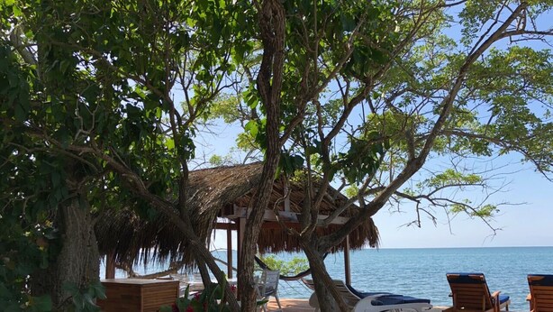 A wooden deck with lounge chairs and a thatched-roof structure overlooking the sea. - Isla Venado. Private Island in Cholon, Cartagena. (Cartagena)