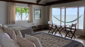 A bedroom with two beds, a desk, a chair, and a view of the sea. - Isla Venado. Private Island in Cholon, Cartagena. (Cartagena)