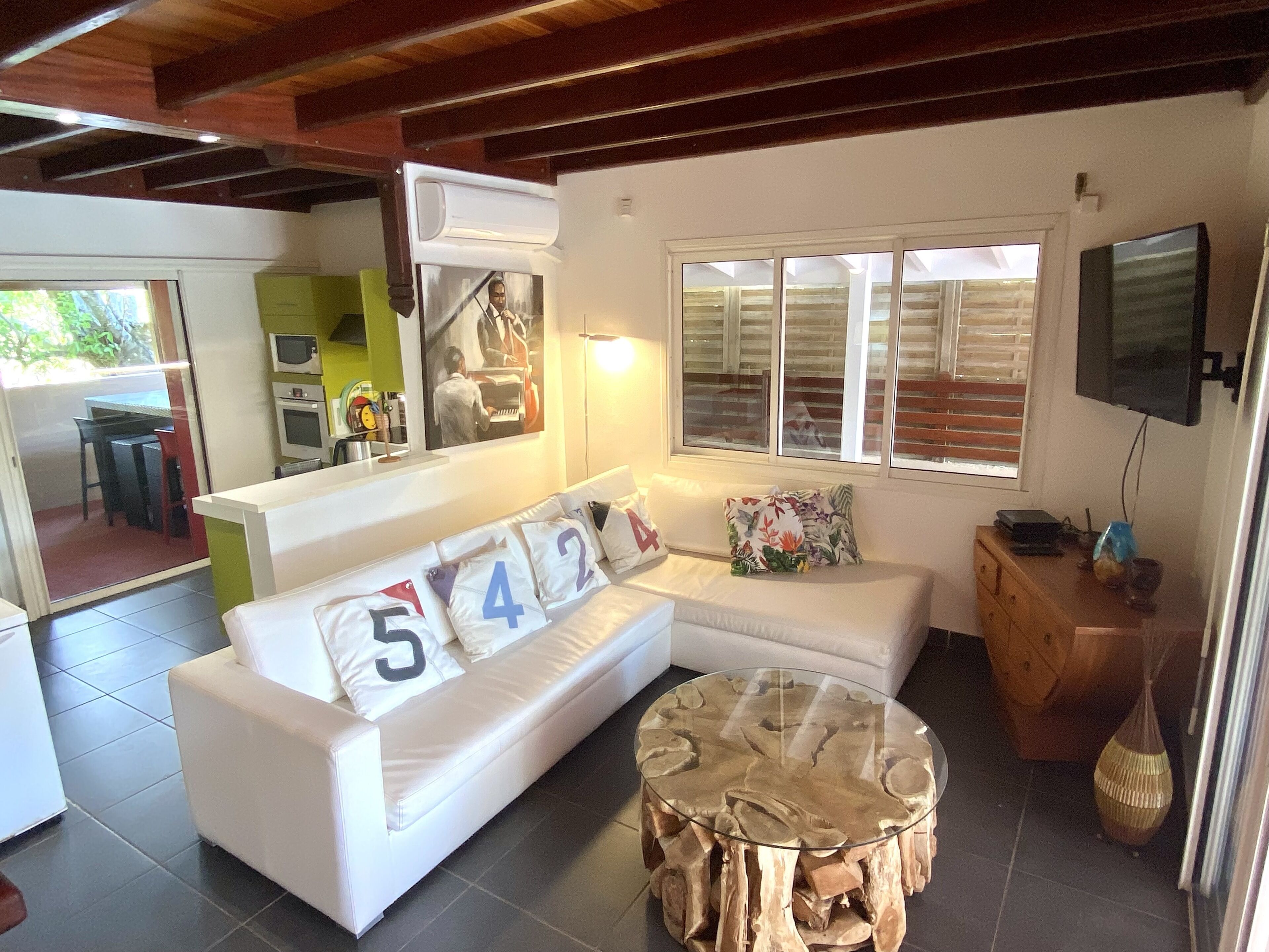 A modern living room with a white sofa, a glass coffee table, and a television mounted on the wall.
