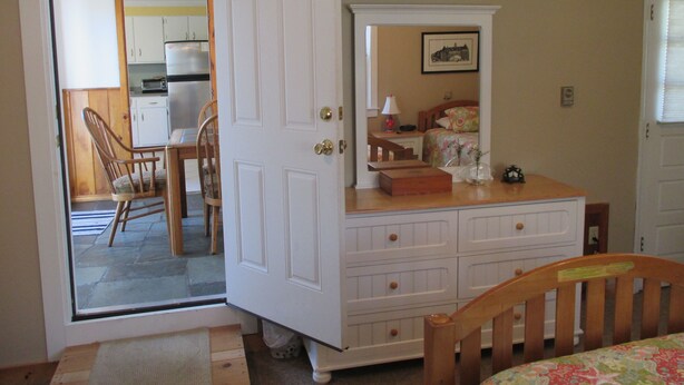 Une chambre à coucher avec un lit en bois, une commode, un miroir et une petite table avec une lampe.