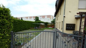Une courClose par un portail, dotée d’un chemin pavé, d’une clôture en métal et d’un bâtiment sur lequel on peut lire l’inscription « Puschkinstraße 37 ».