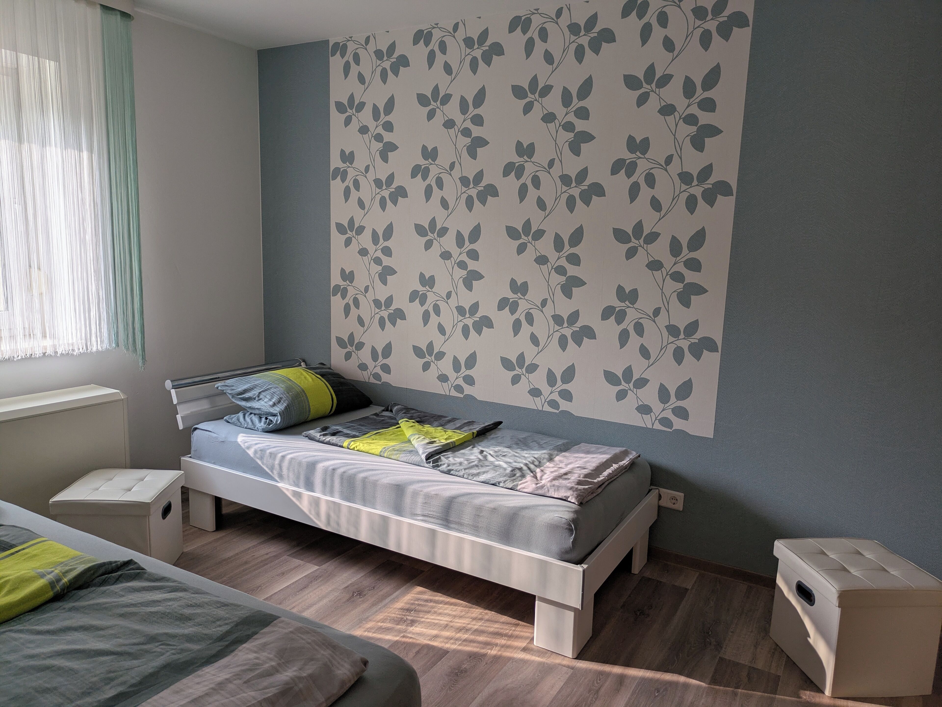 Un dormitorio con cama, mesitas de noche y ventana con cortinas.