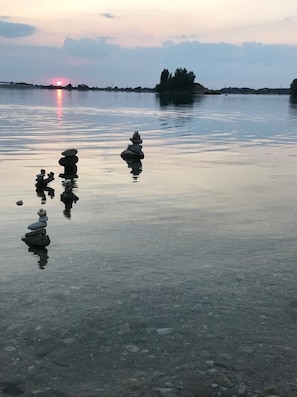 Un lago tranquillo con rocce ammassate e un tramonto sullo sfondo.