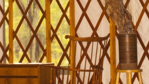 Une tente à structure en treillis, des meubles en bois et une plante en pot.