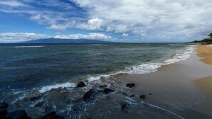 A beach with waves, a clear sky, and a distant mountain. - Oceanfront, adjacent to North Ka'anapali Beach, Central A/C! Newly reduced rates (Lahaina)