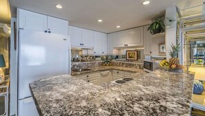 A modern kitchen with white cabinets, granite countertops, and a central island. - Oceanfront, adjacent to North Ka'anapali Beach, Central A/C! Newly reduced rates (Lahaina)