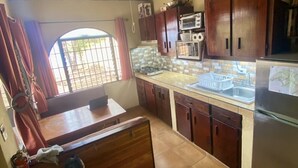 Une cuisine de taille réduite, dotée de meubles en bois, d’une cuisinière à gaz, d’un four à micro-ondes et d’un réfrigérateur.