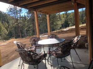 A covered patio with a round table and four chairs, surrounded by a wooden pergola.