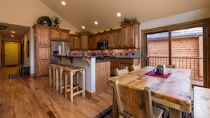 A kitchen with wooden cabinets, a stainless steel refrigerator, a microwave, and a dining area with a wooden table and chairs.