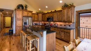 A kitchen with wooden cabinets, a stainless steel refrigerator, a microwave, and a wooden dining table with chairs.