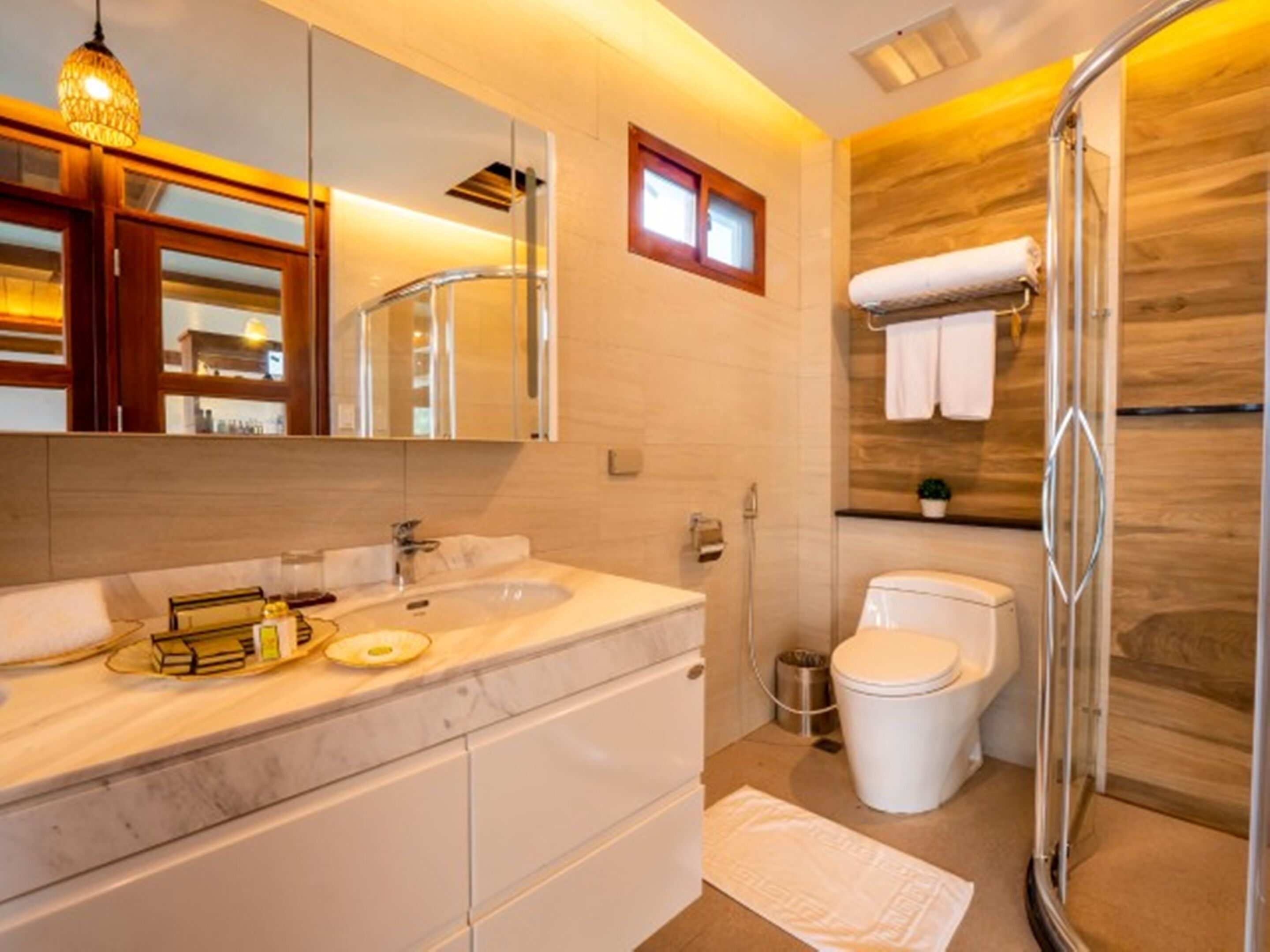 Une salle de bain moderne avec un lavabo en marbre, une cabine de douche en verre et un mur d’accent en bois.