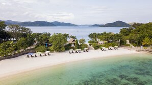 Ett semesterparadis vid stranden med kristallklart turkost vatten, en sandstrand och solstolar.