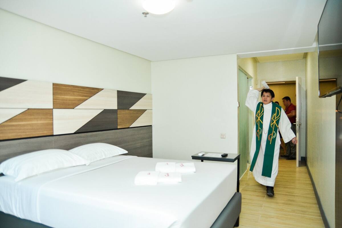 A hotel room with a bed, a bedside table, and a wall with a geometric pattern.