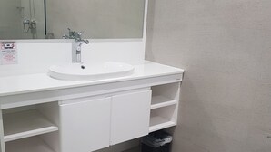 A bathroom with a white sink, mirror, and toilet. - Travelite Hotel Legarda (Baguio)