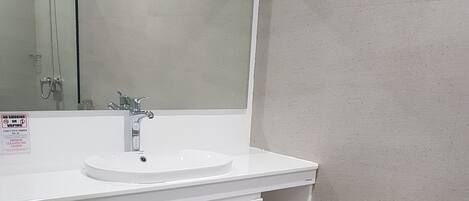 A bathroom with a white sink, mirror, and toilet.