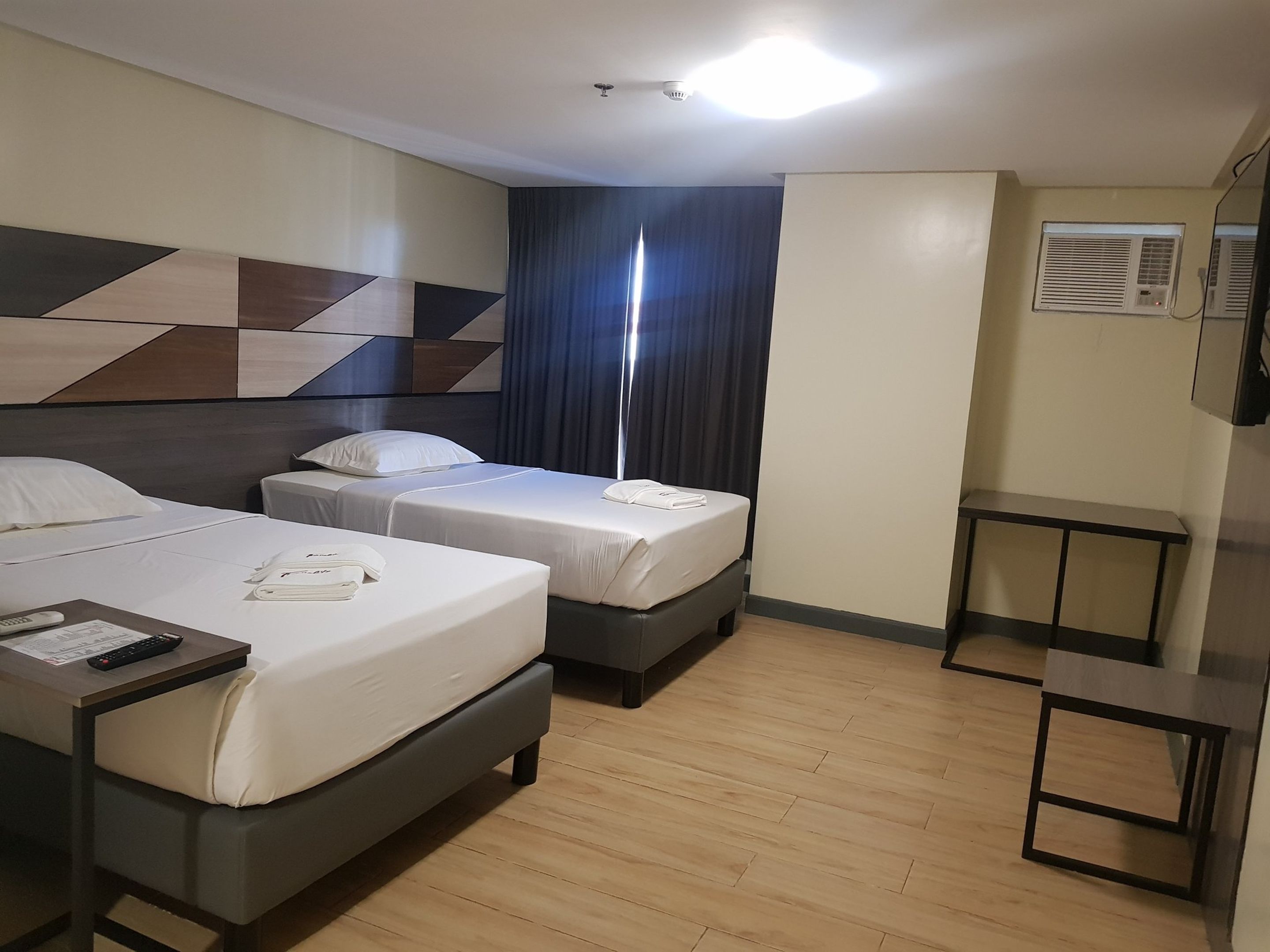 A hotel room with two beds, a desk, and a mirror.
