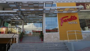 A modern hotel with a colorful facade, a prominent entrance with a staircase, and a clear view of the interior through the glass doors. - Travelite Hotel Legarda (Baguio)