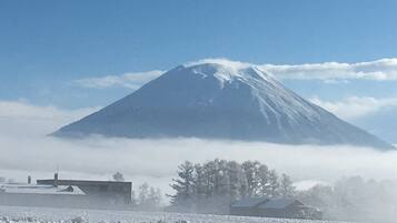 A snow-covered landscape with a prominent mountain and a few buildings in the foreground.