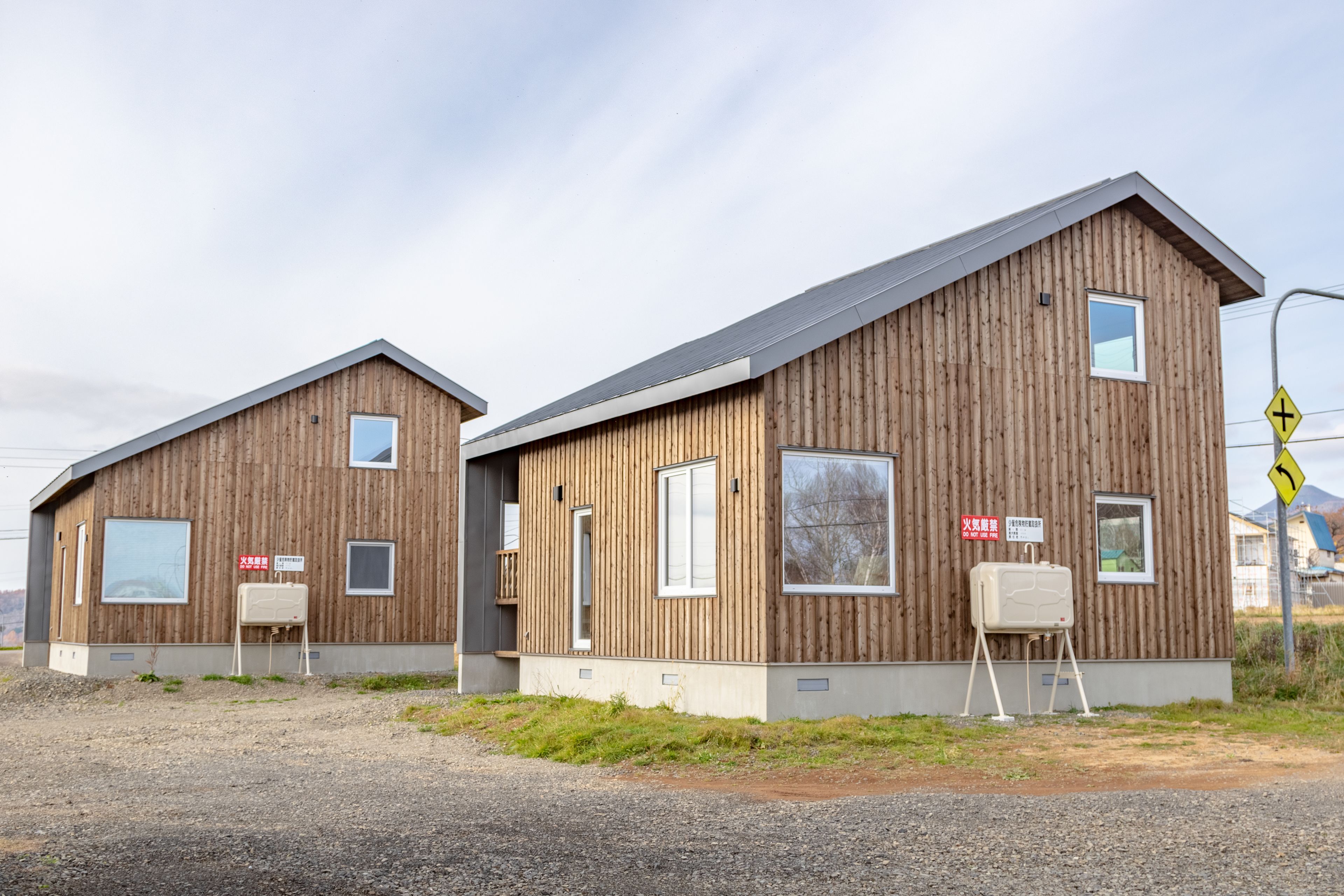 Two wooden buildings with a simple design, featuring large windows and a small porch area.