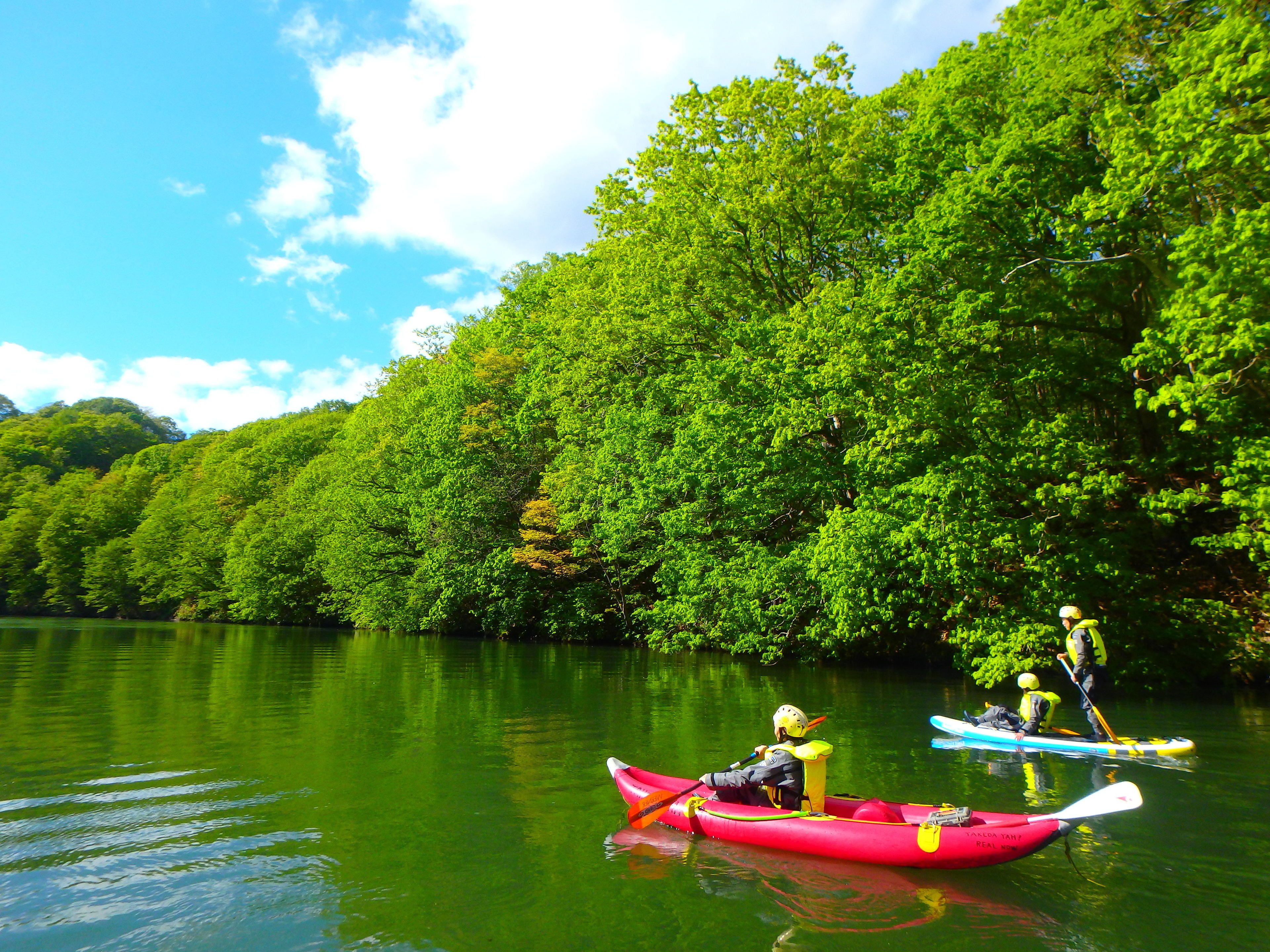A calm river with kayaks and a person paddling.