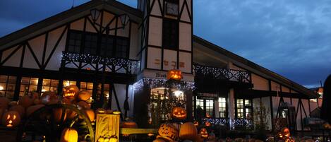 Un edificio con una torre de reloj y numerosas ventanas, rodeado de calabazas y decoraciones de Halloween.