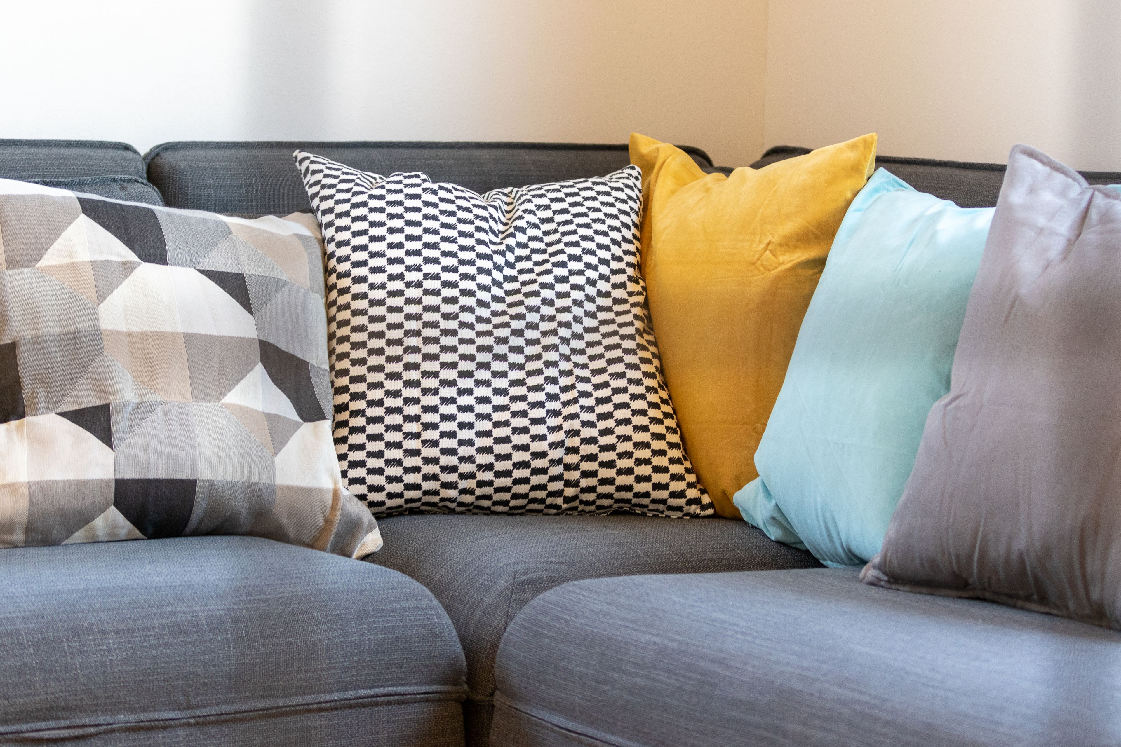 A gray sofa with multiple pillows in various patterns and colors.