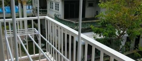 A balcony with a metal railing and a view of a building with a red roof.