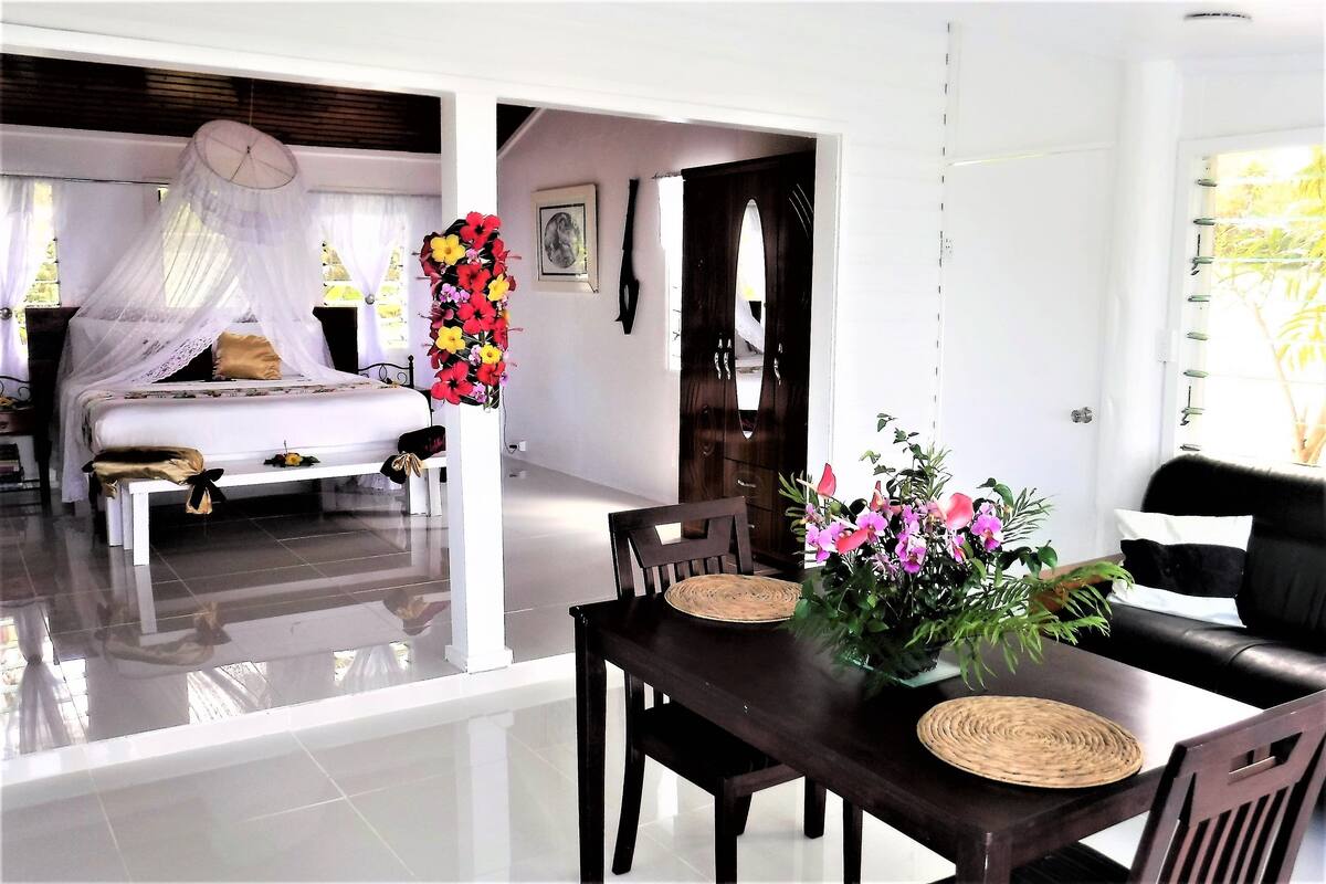 Una habitación de hotel con cama, una mesa de comedor con sillas, un rincón de comedor y una sala de estar con sofá.