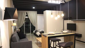 A modern living room with a sofa, a dining area with a bar, and a TV mounted on the wall. - Twin Galaxy Suites (Johor Bahru)