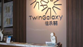 A reception desk with a sign reading "TwinGalaxy" and a decorative sun-like design above it.